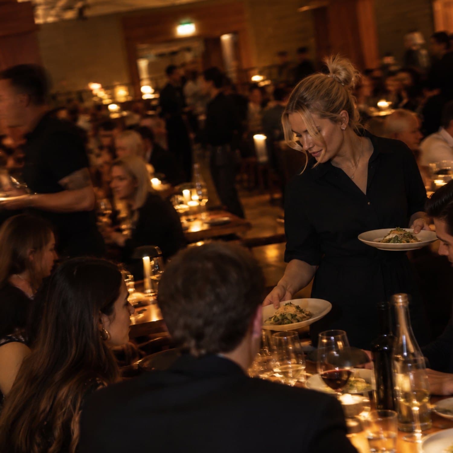 Servitris serverar maten vid ett bord på en fullsatt restaurang
